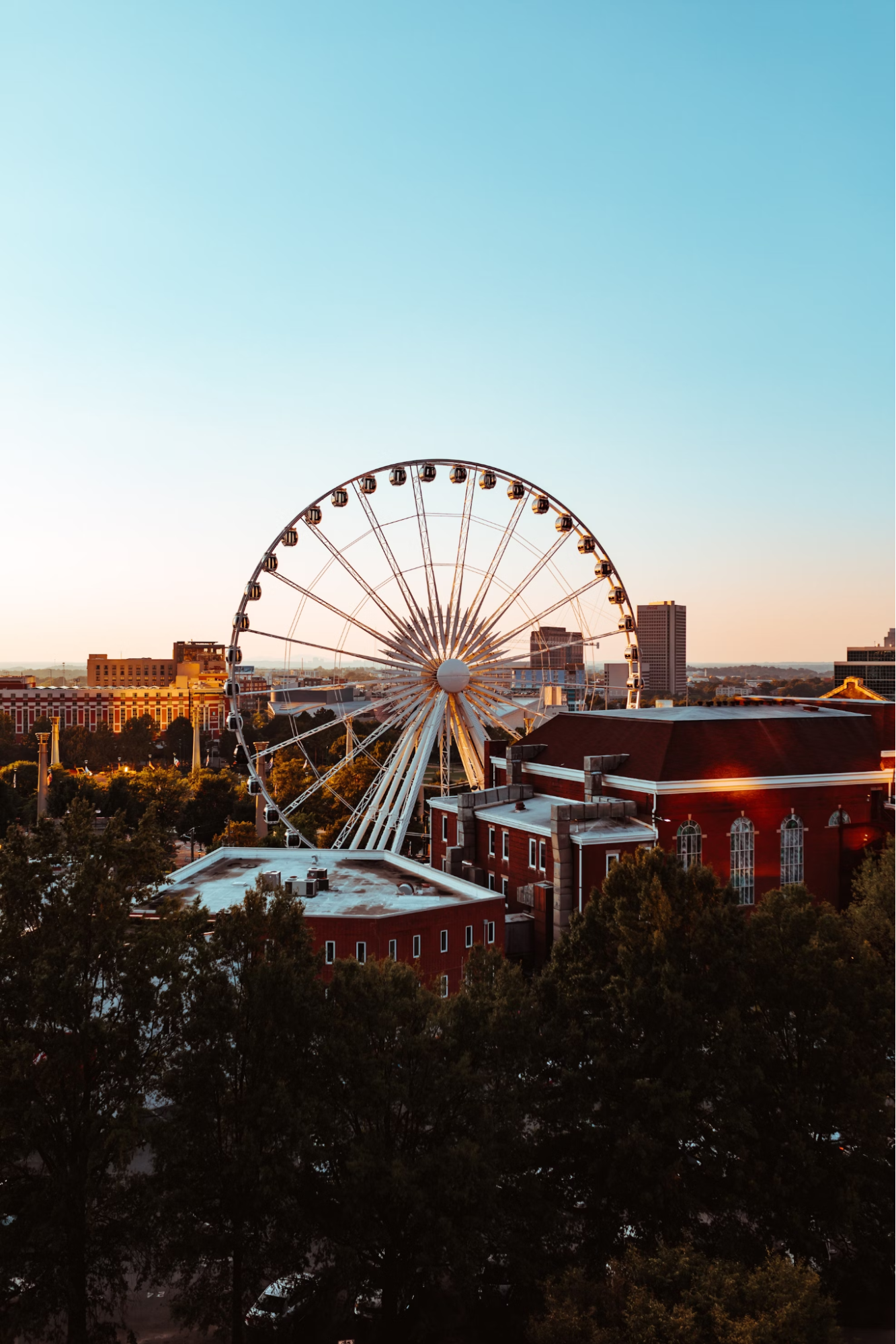 Ferris wheel rising above buildings in downtown Atlanta at sunset