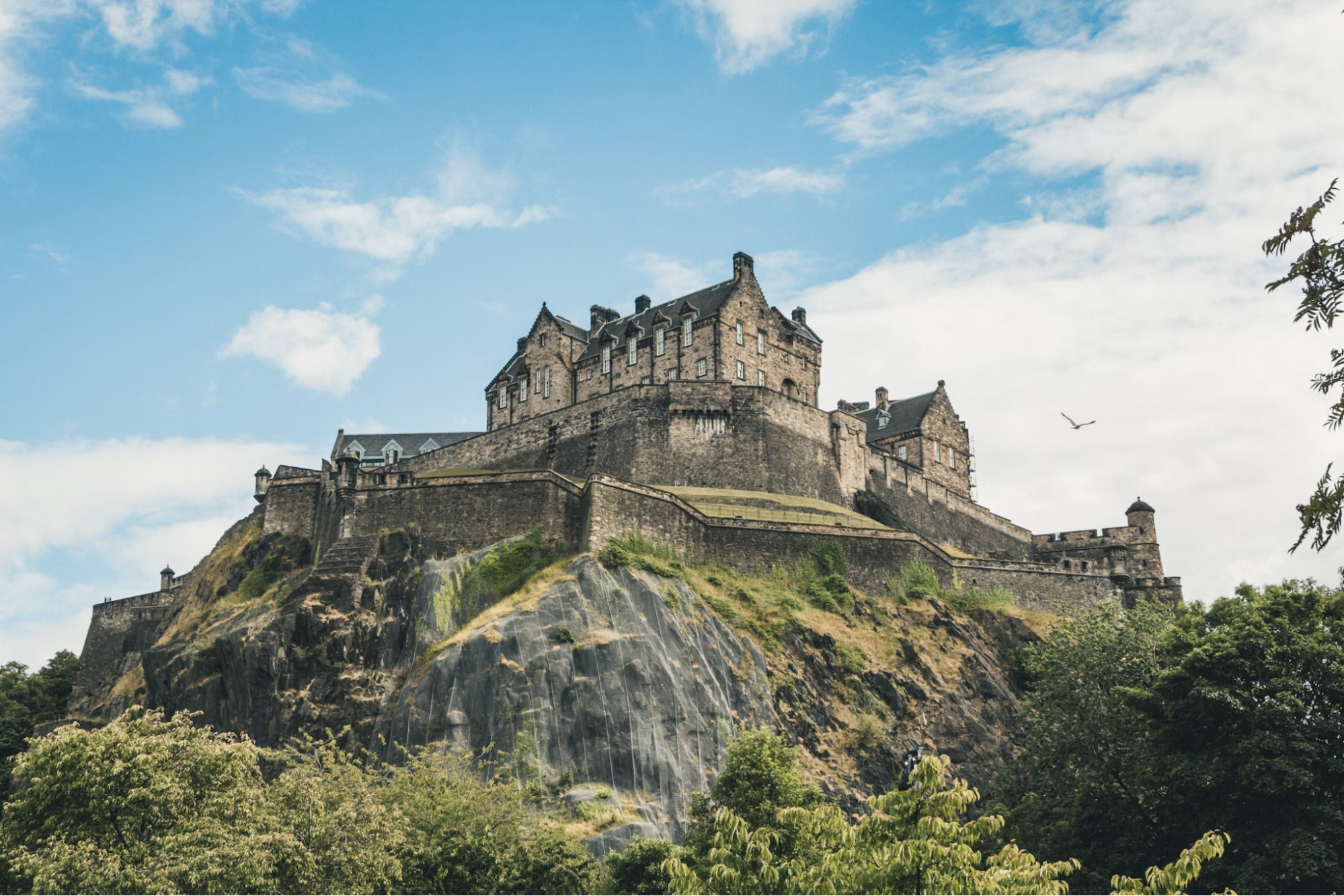 Edinburgh Castle on a rocky hill under a partly cloudy sky