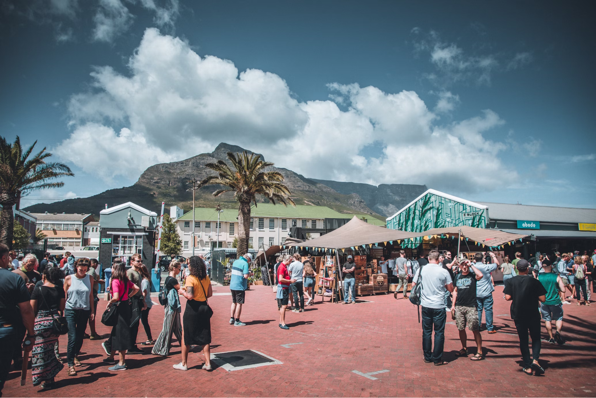 People gathering at Neighbourgoods Market in Cape Town under a sunny sky with Table Mountain in the background