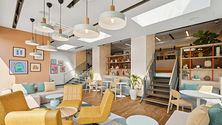 Bright hotel lobby with modern seating, pastel decor and skylights