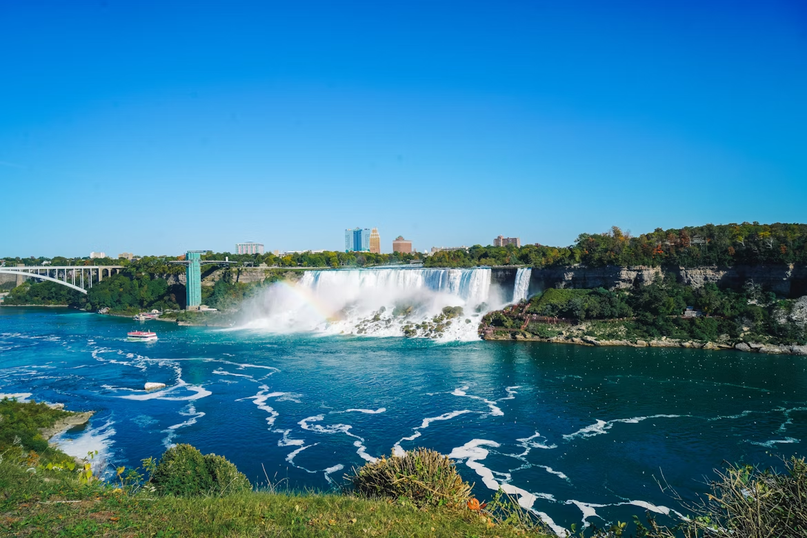 View of Niagara Falls with a visible rainbow and tour boat on the river