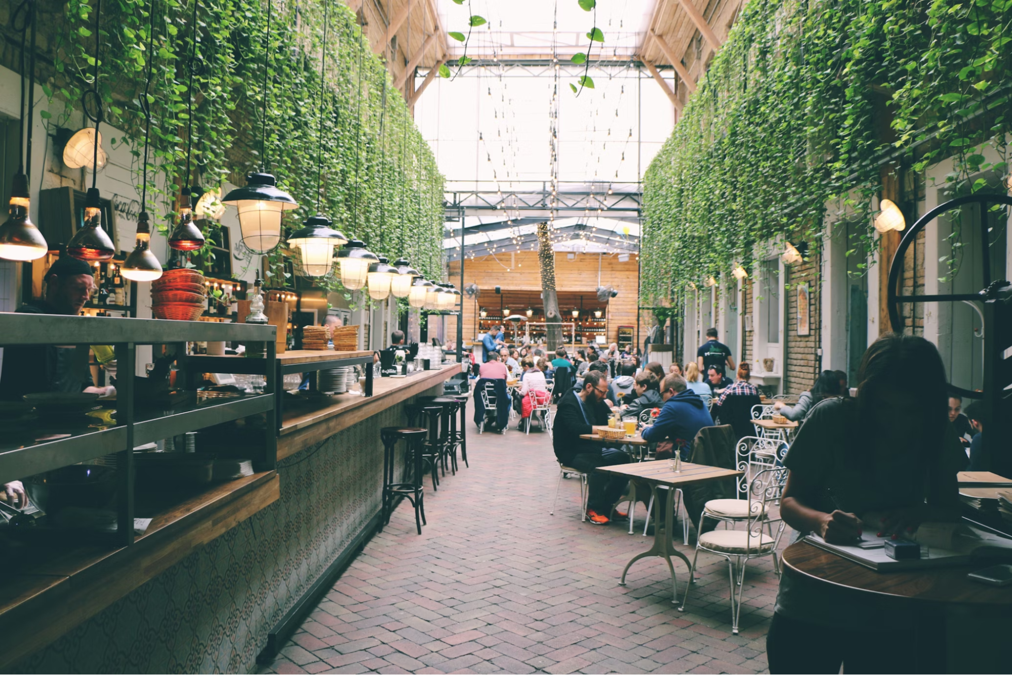 Indoor food hall with hanging greenery and seated diners