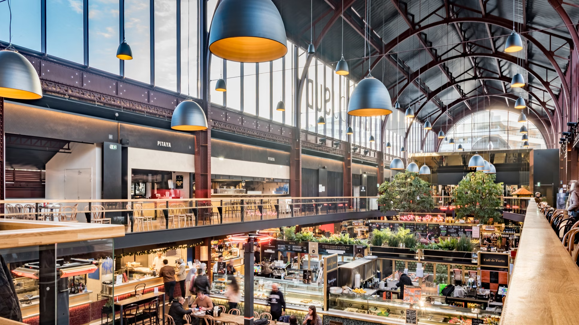 Interior of a busy European food hall with high ceilings and multiple food stalls