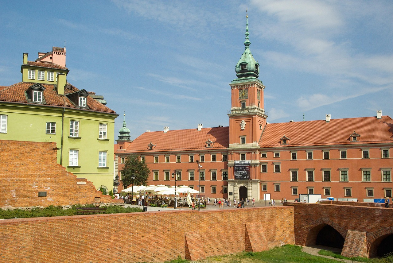 The Royal Castle in Warsaw with historic buildings and red brick walls under a blue sky