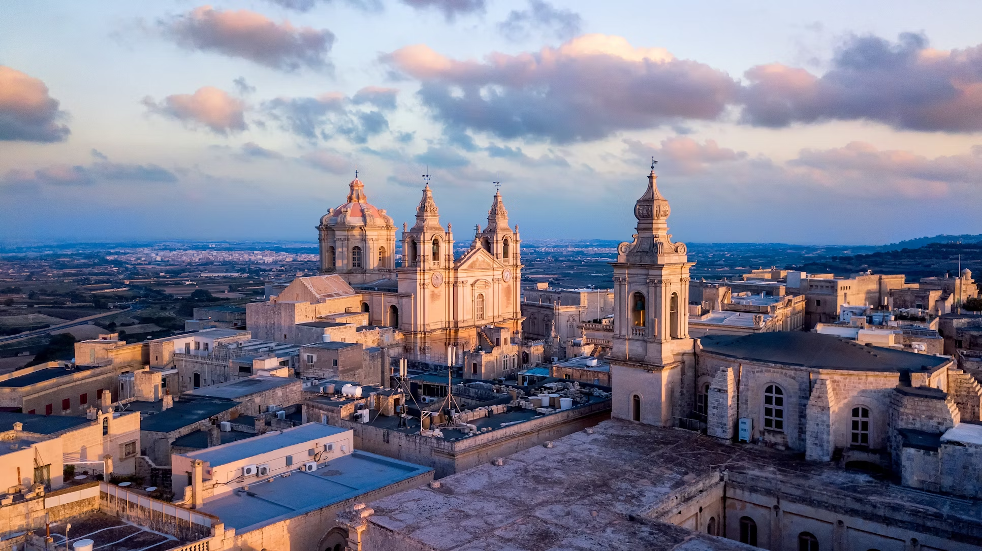 Aerial view of Mdina, Malta at sunset with historic buildings and church towers
