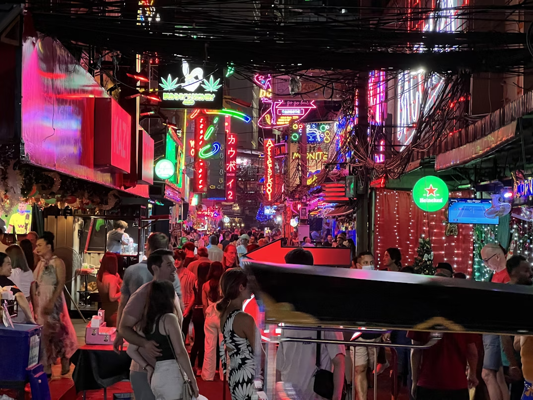 Crowds walking through neon-lit Soi Cowboy nightlife street in Bangkok
