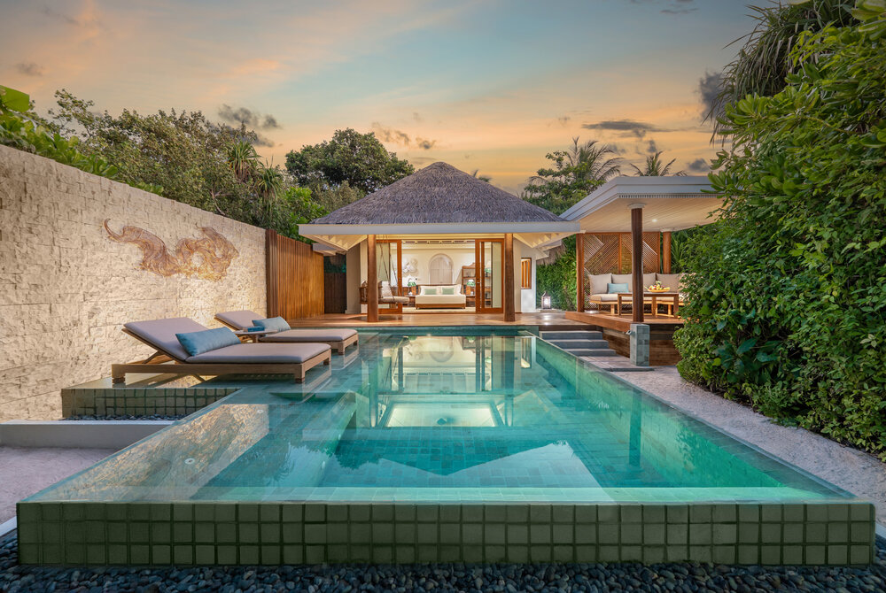 Exterior view of a luxurious Beach Pool Villa with a private pool surrounded by greenery at sunset