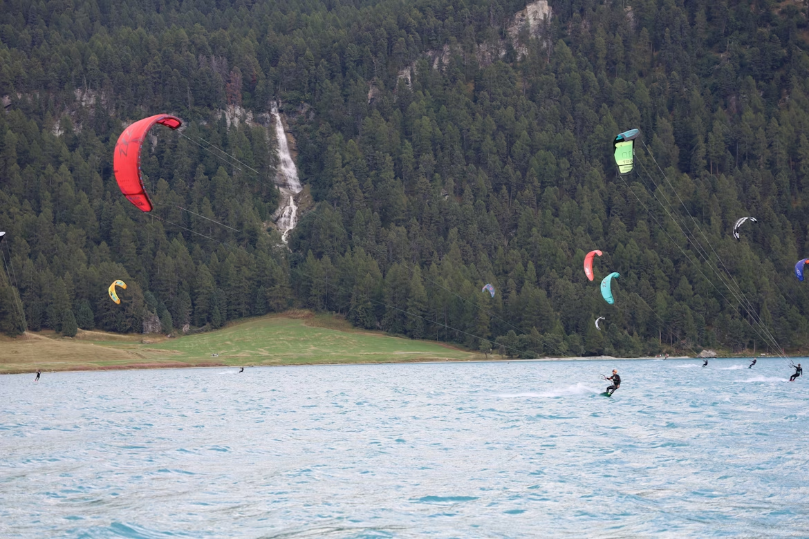 Kitesurfers on Lake Silvaplana with forested mountains in the background