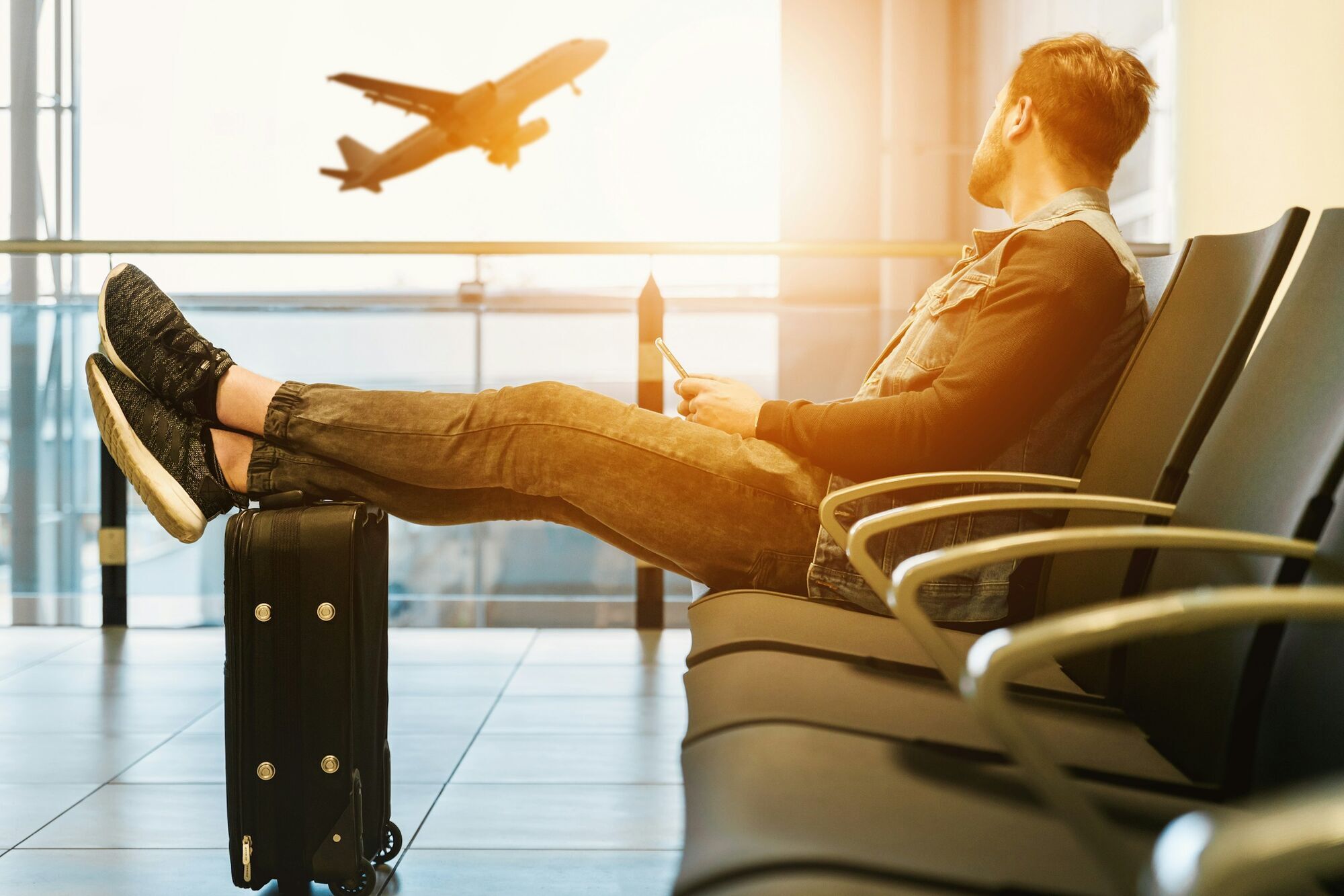 Traveler at airport lounge using phone with airplane in background