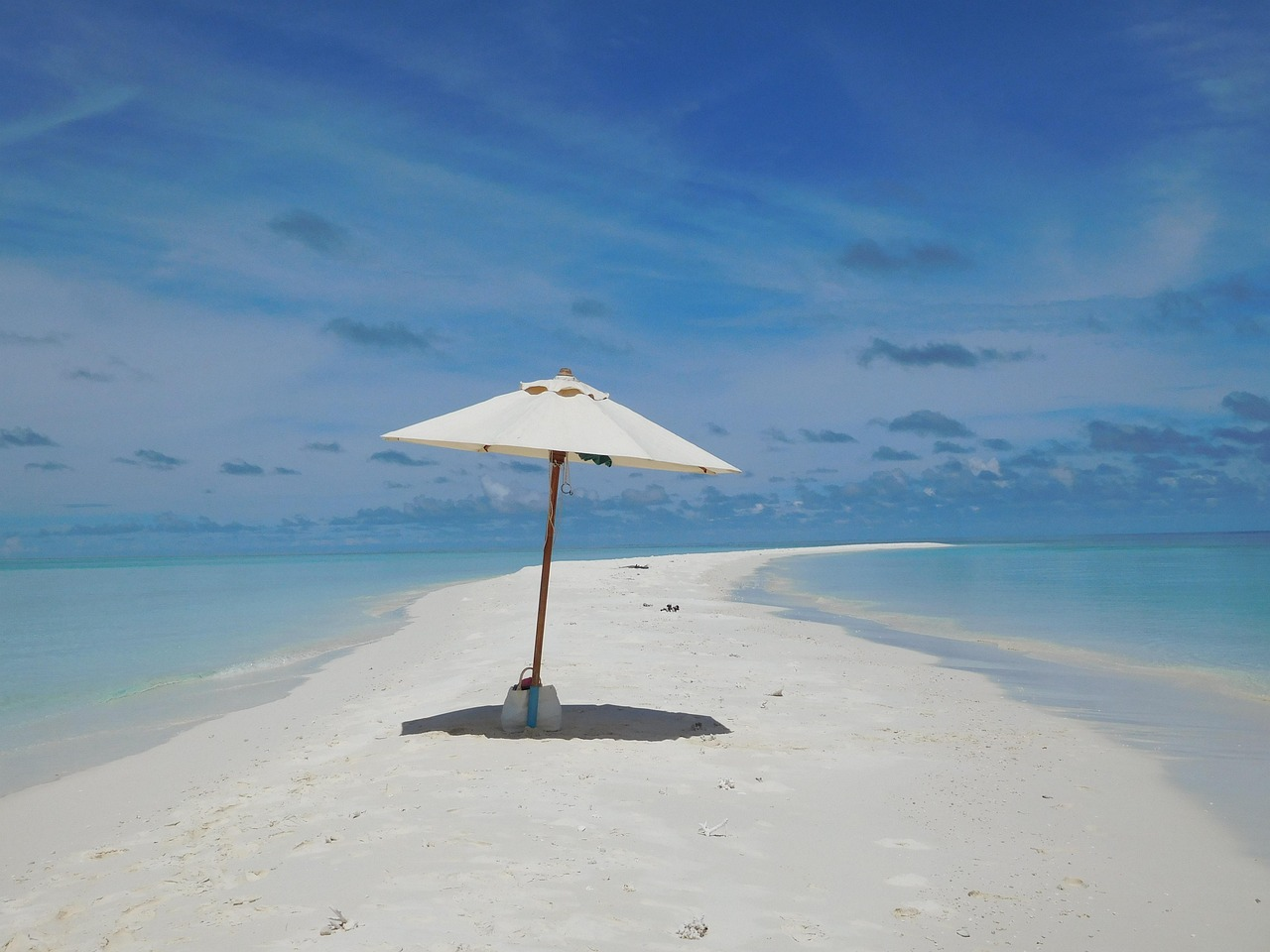 Solitary umbrella on Kandima Sandbank surrounded by turquoise waters and blue sky