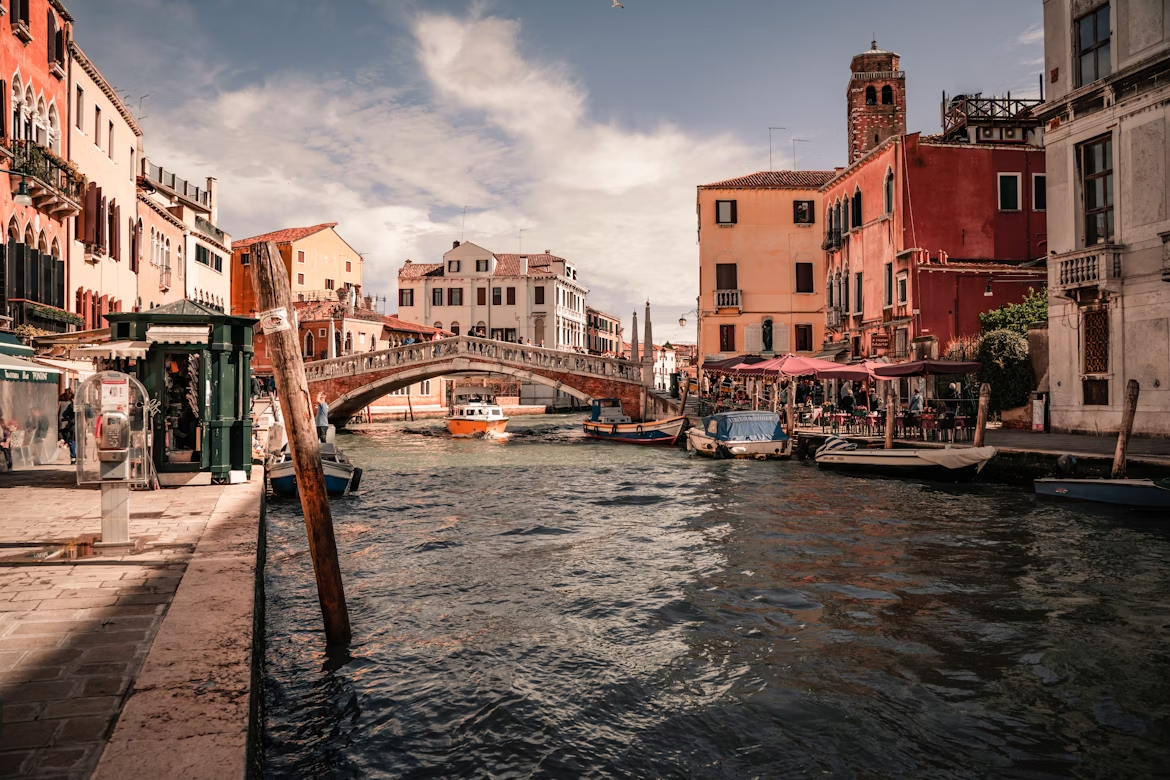 Canal in Venice with bridge, waterfront cafés and moored boats