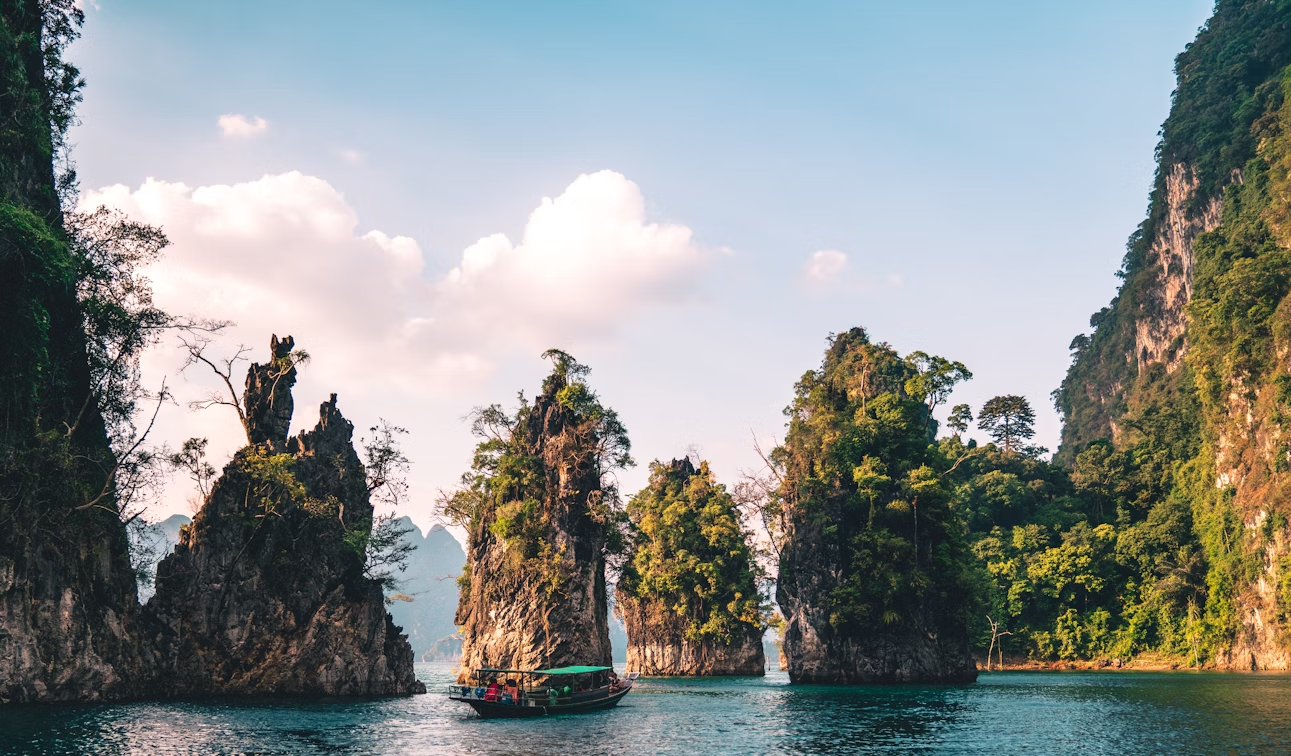 Scenic view of limestone cliffs and boat on turquoise water in a tropical bay