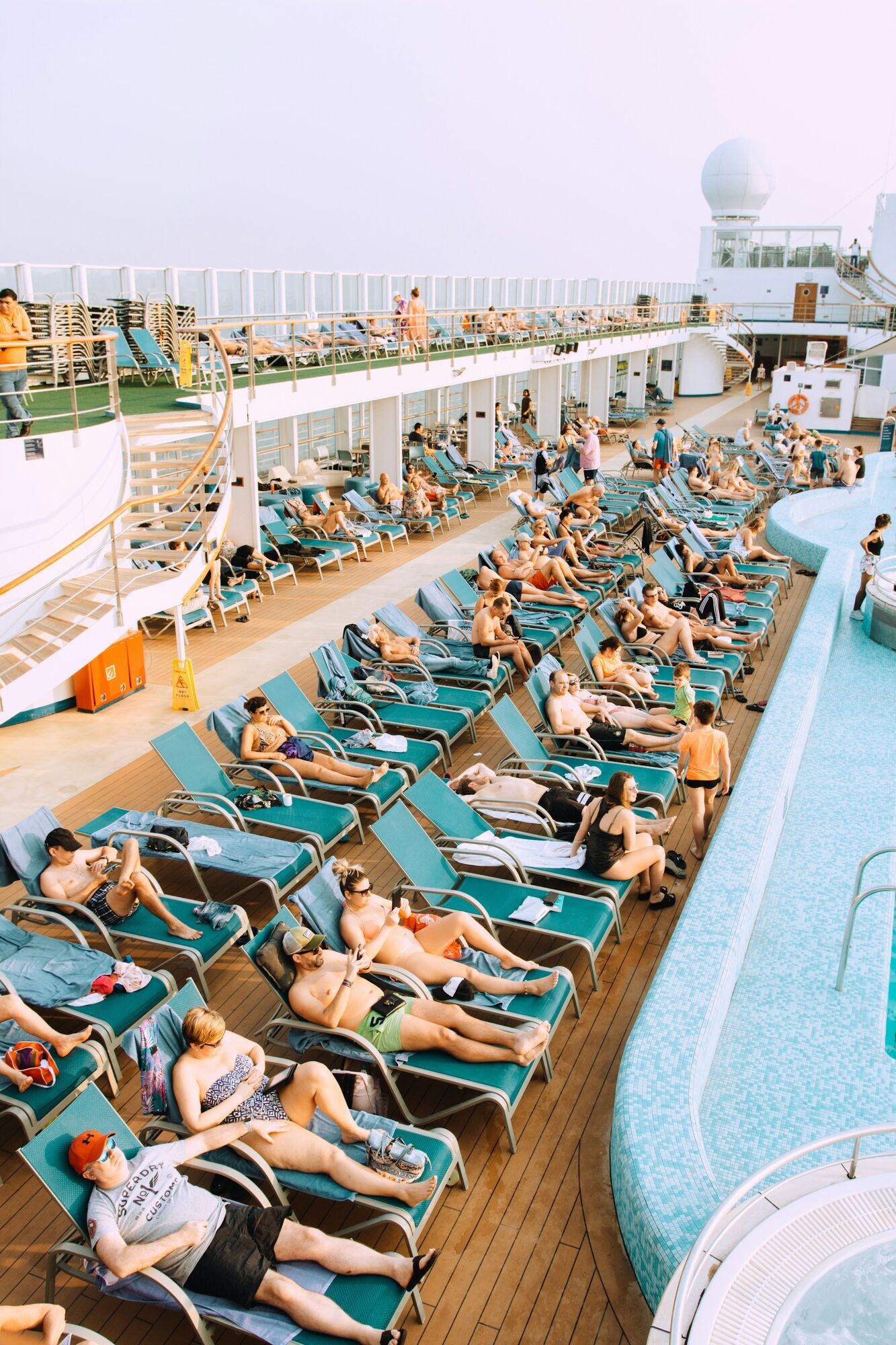 Cruise passengers relaxing on sun loungers by the pool