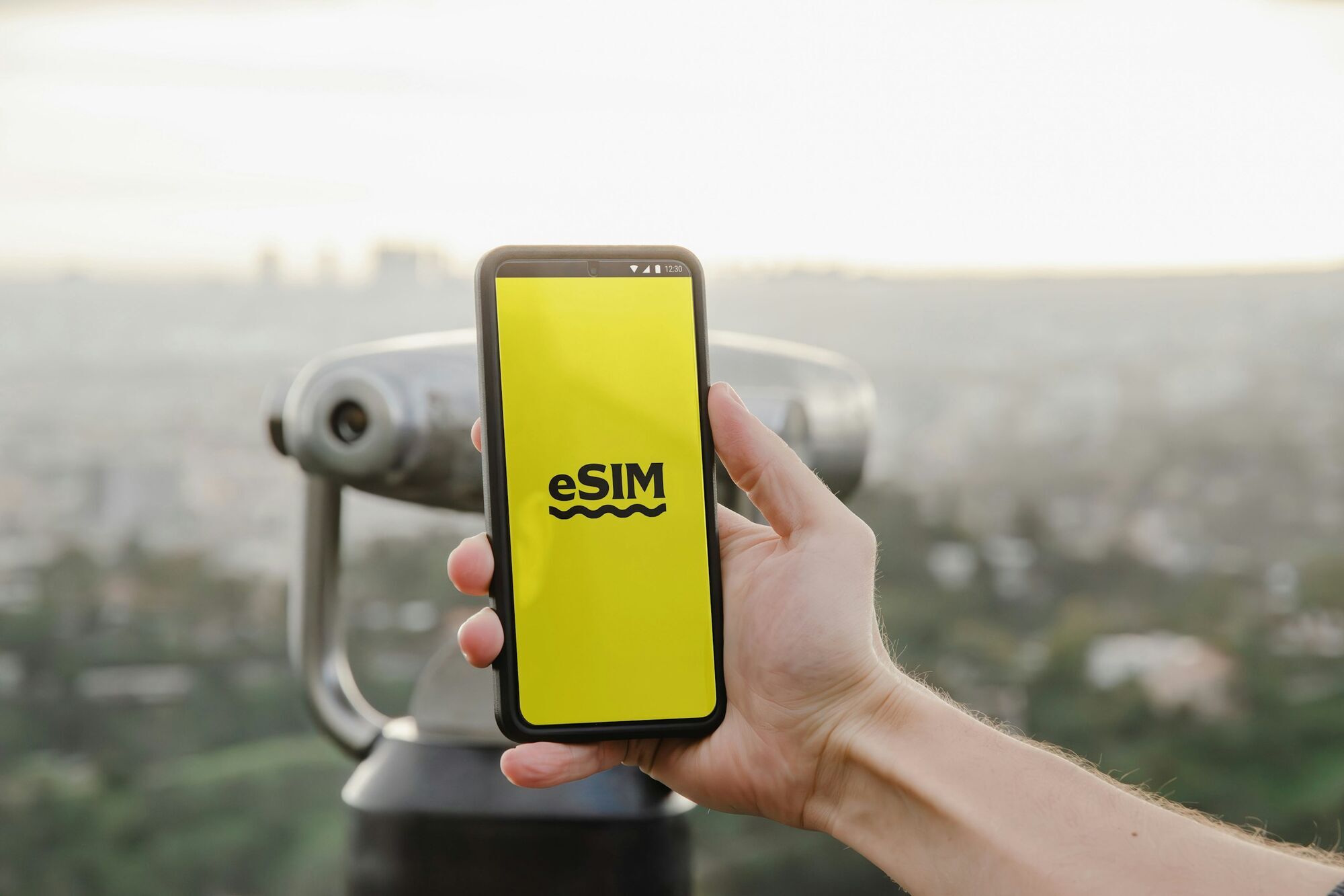 Hand holding a smartphone displaying an eSIM logo