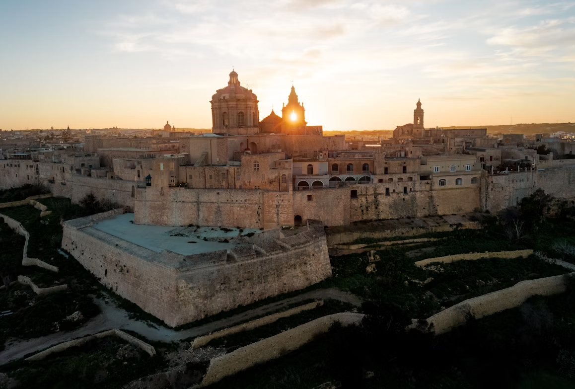 View of Mdina, Malta at sunset with historic stone buildings and fortifications