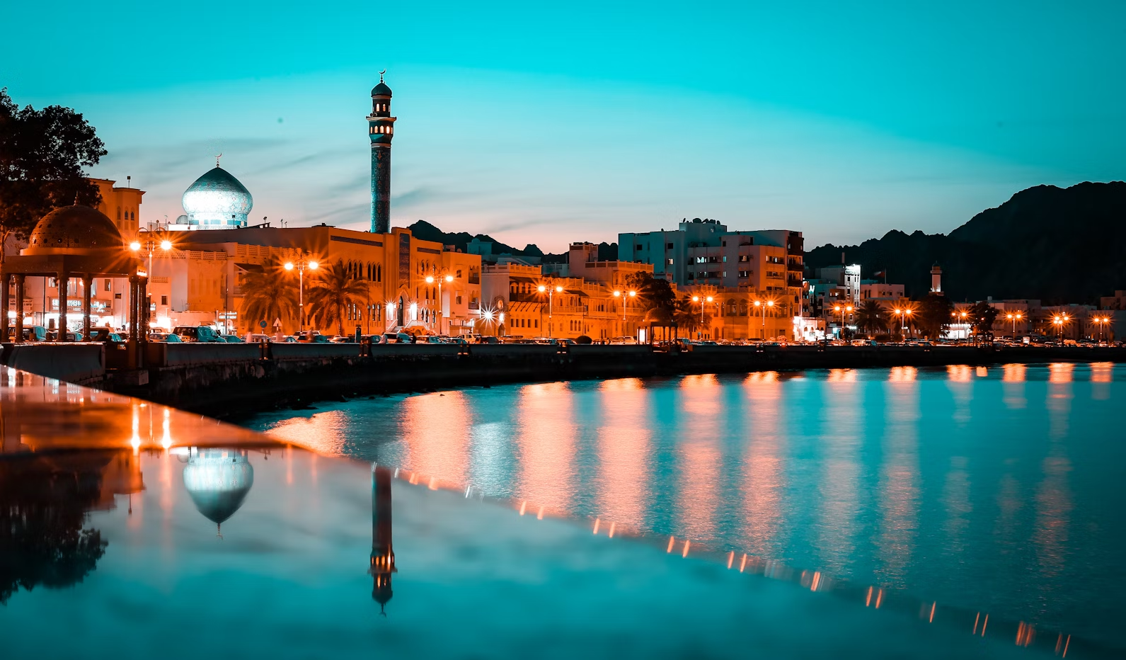 Muscat waterfront with mosque and city lights at dusk