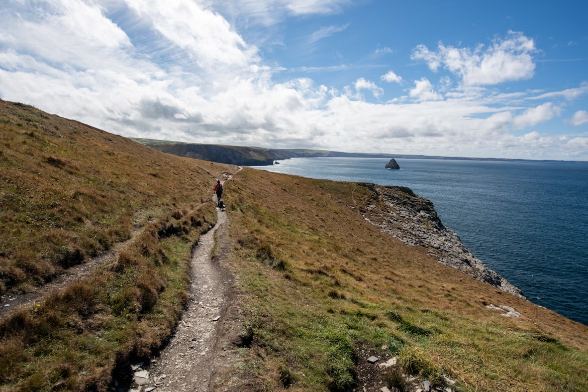 Hiker walking along South West Coast Path overlooking the sea