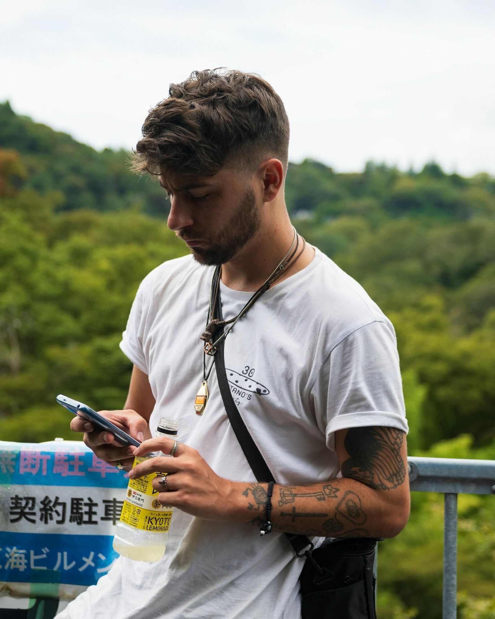 Traveler using a smartphone outdoors, checking connectivity options while holding a drink