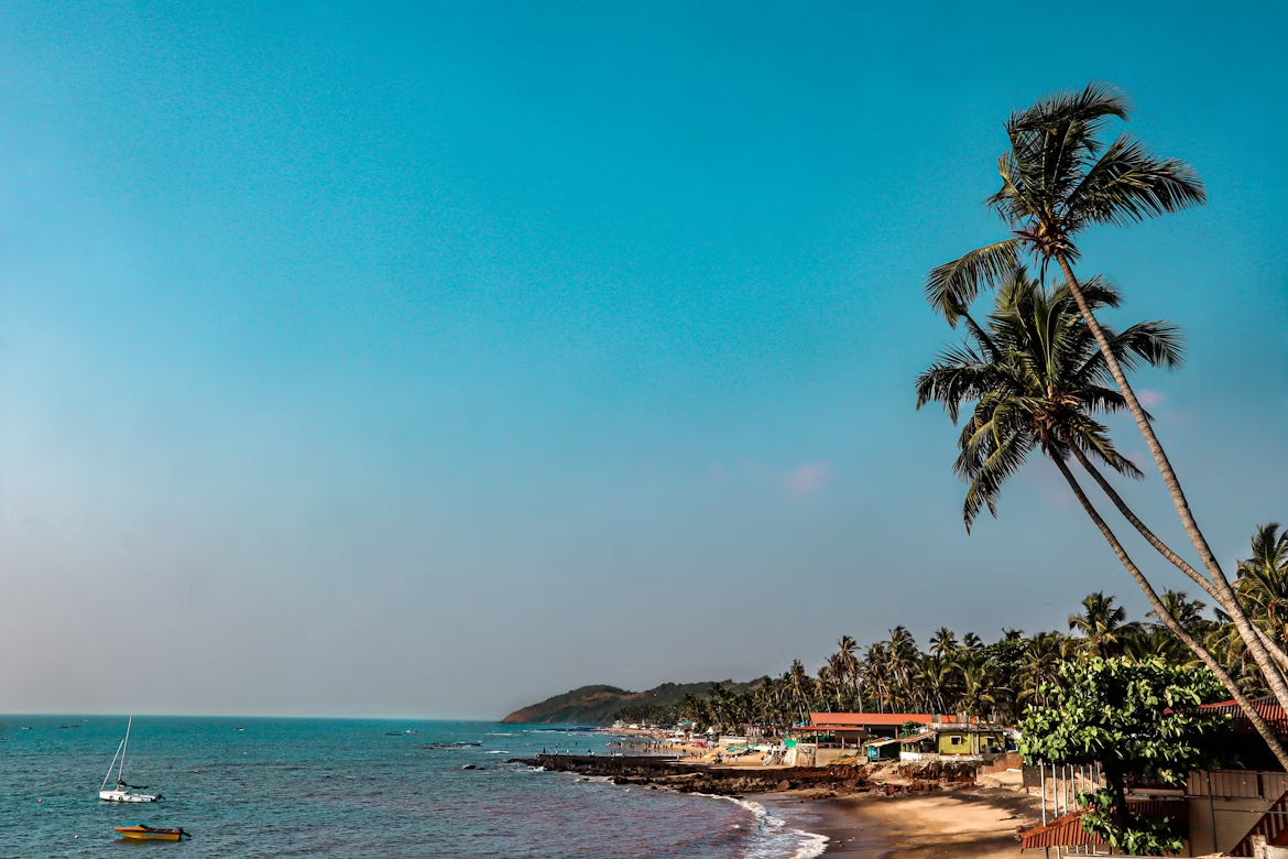 Coastal view of Anjuna Beach with palm trees and seaside buildings