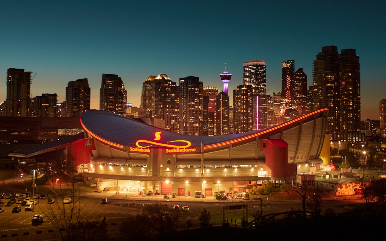 Scotiabank Saddledome lit at night with Calgary skyline in background