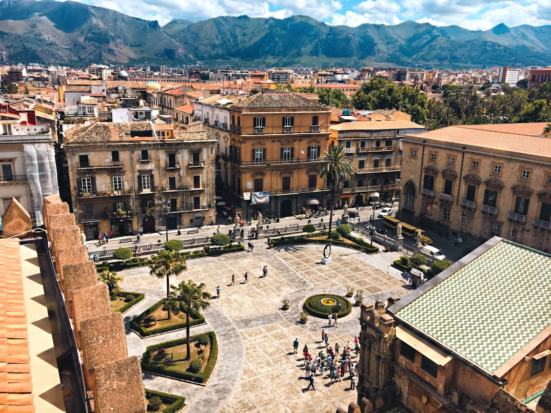 Aerial view of a square in Palermo with historic buildings and mountains in the background