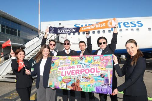 SunExpress crew holding a welcome banner at Liverpool Airport