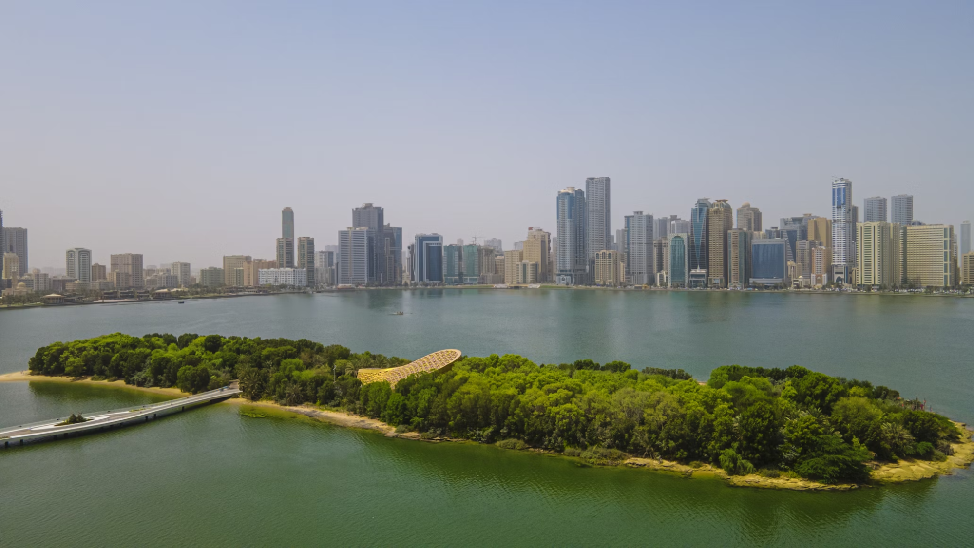 Sharjah city skyline with waterfront and green island in the foreground