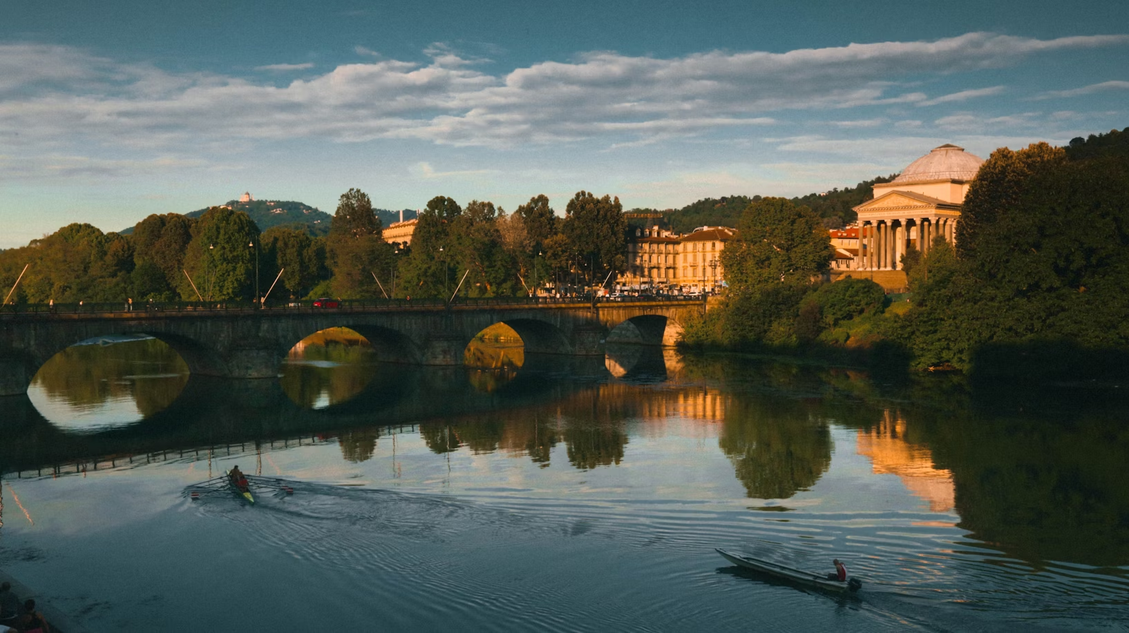 View of the Po River with rowing boats, bridge, and the Gran Madre di Dio church in Turin at sunset