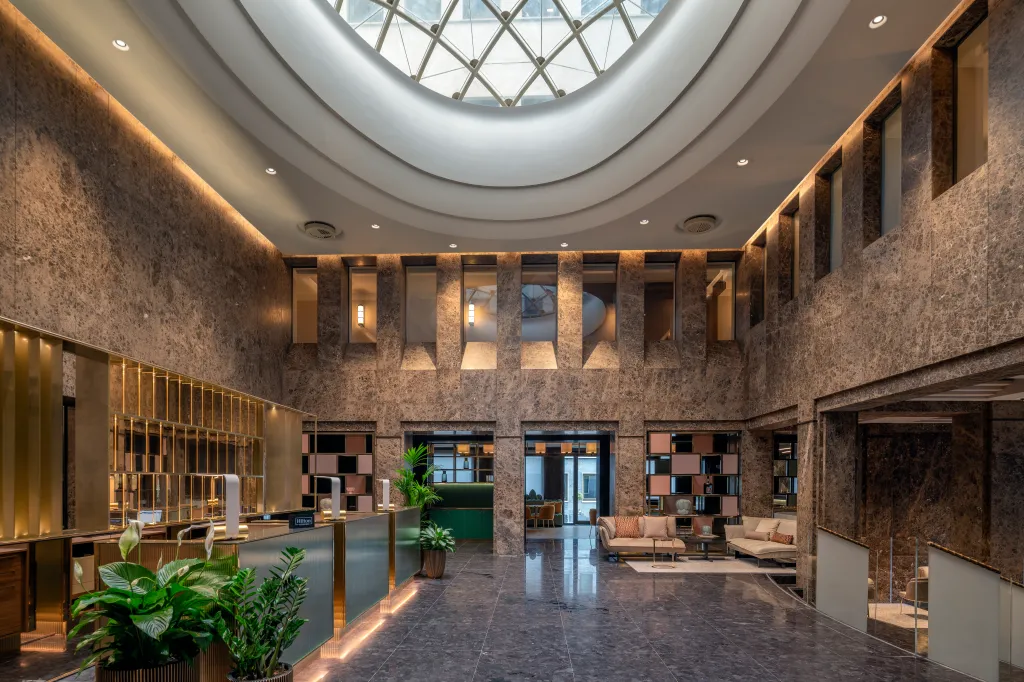 Interior of Hilton Turin Centre lobby with marble walls and skylight