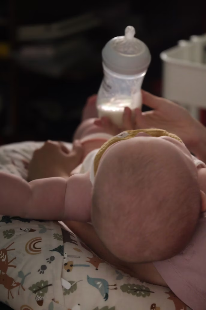 Baby lying on a pillow being bottle-fed