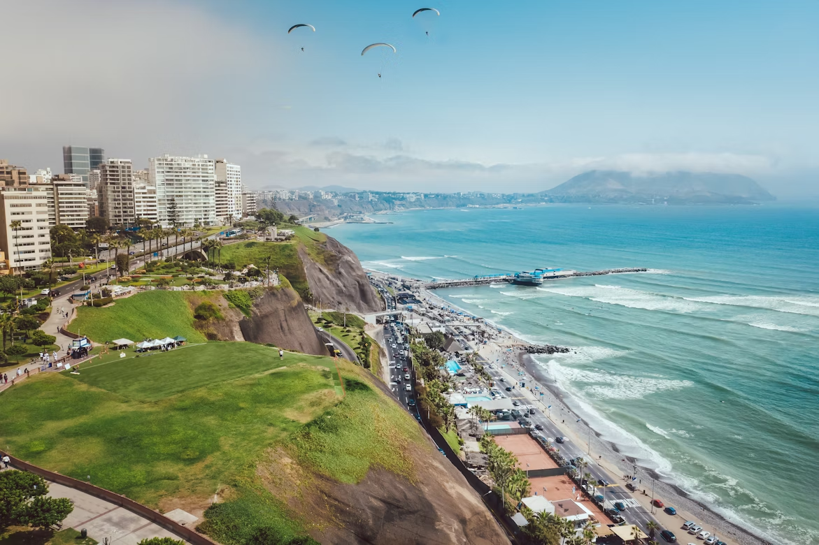Aerial view of Miraflores cliffs, coastline, and ocean with paragliders overhead