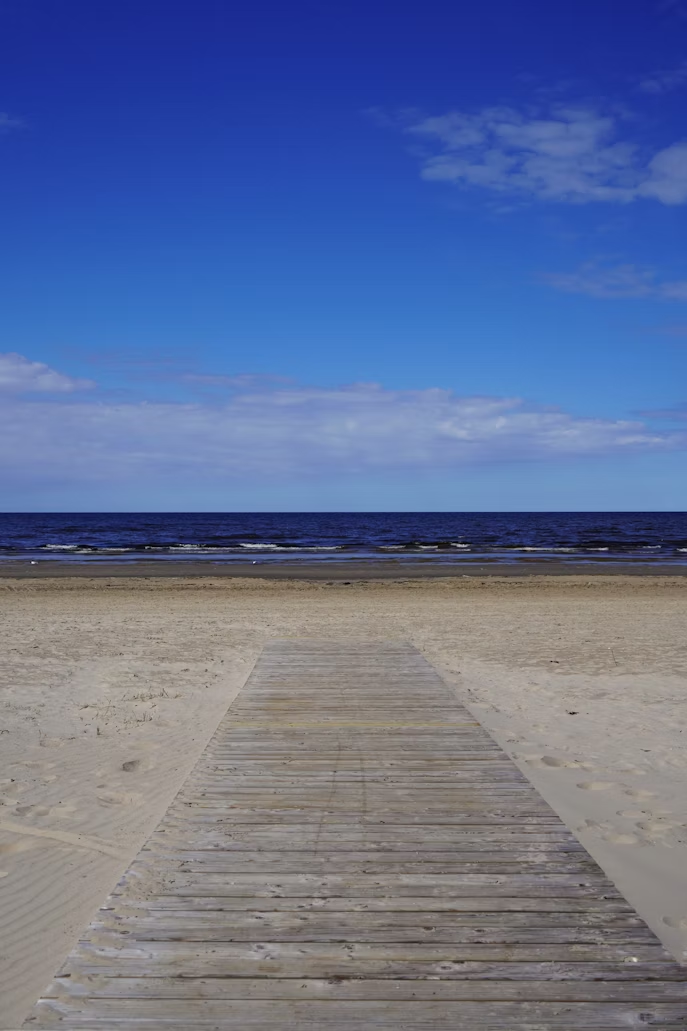 Wooden boardwalk leading to Jūrmala Beach under a blue sky