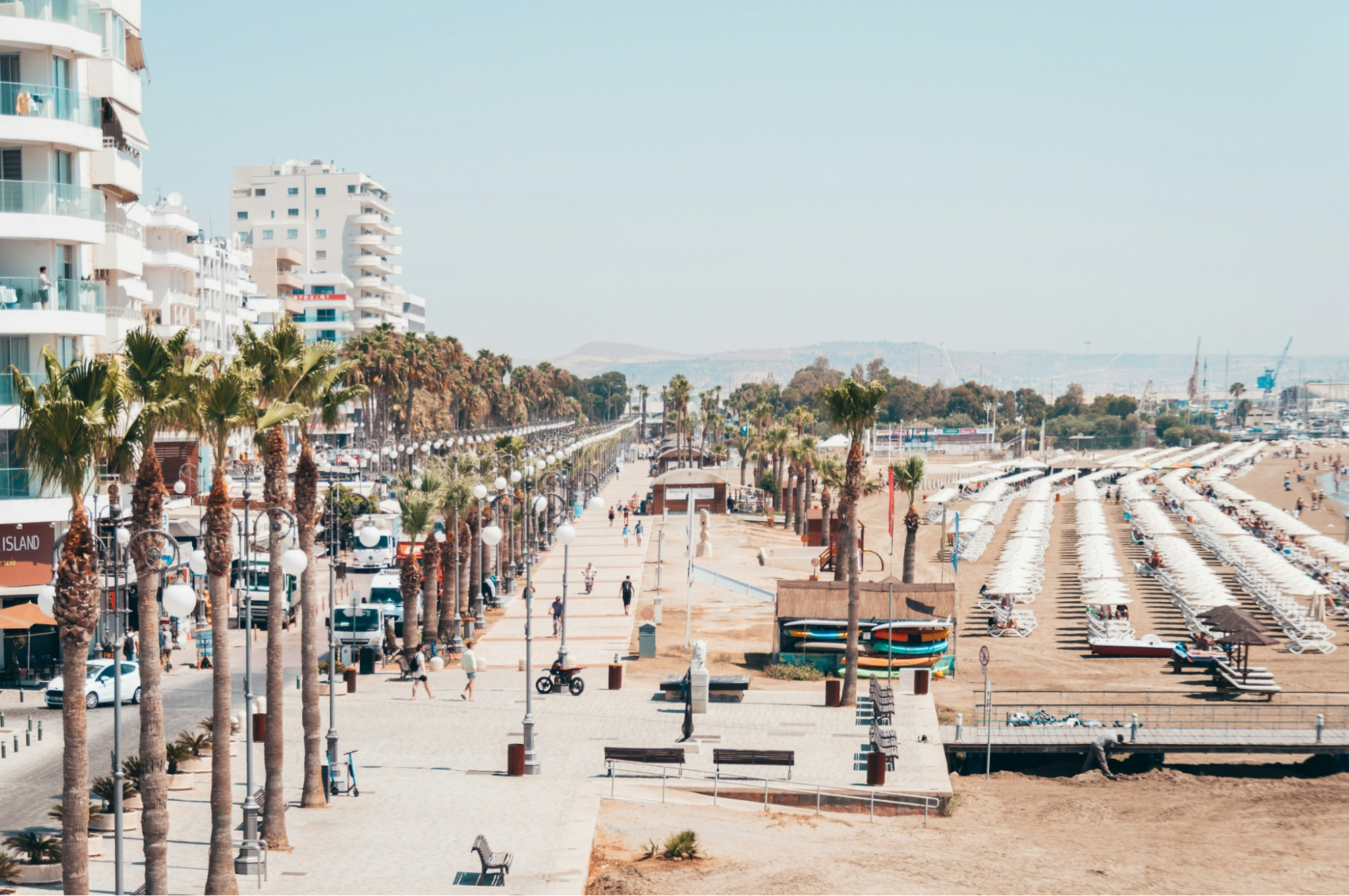 Larnaca beachfront with promenade, palm trees and sunbeds on a sunny day