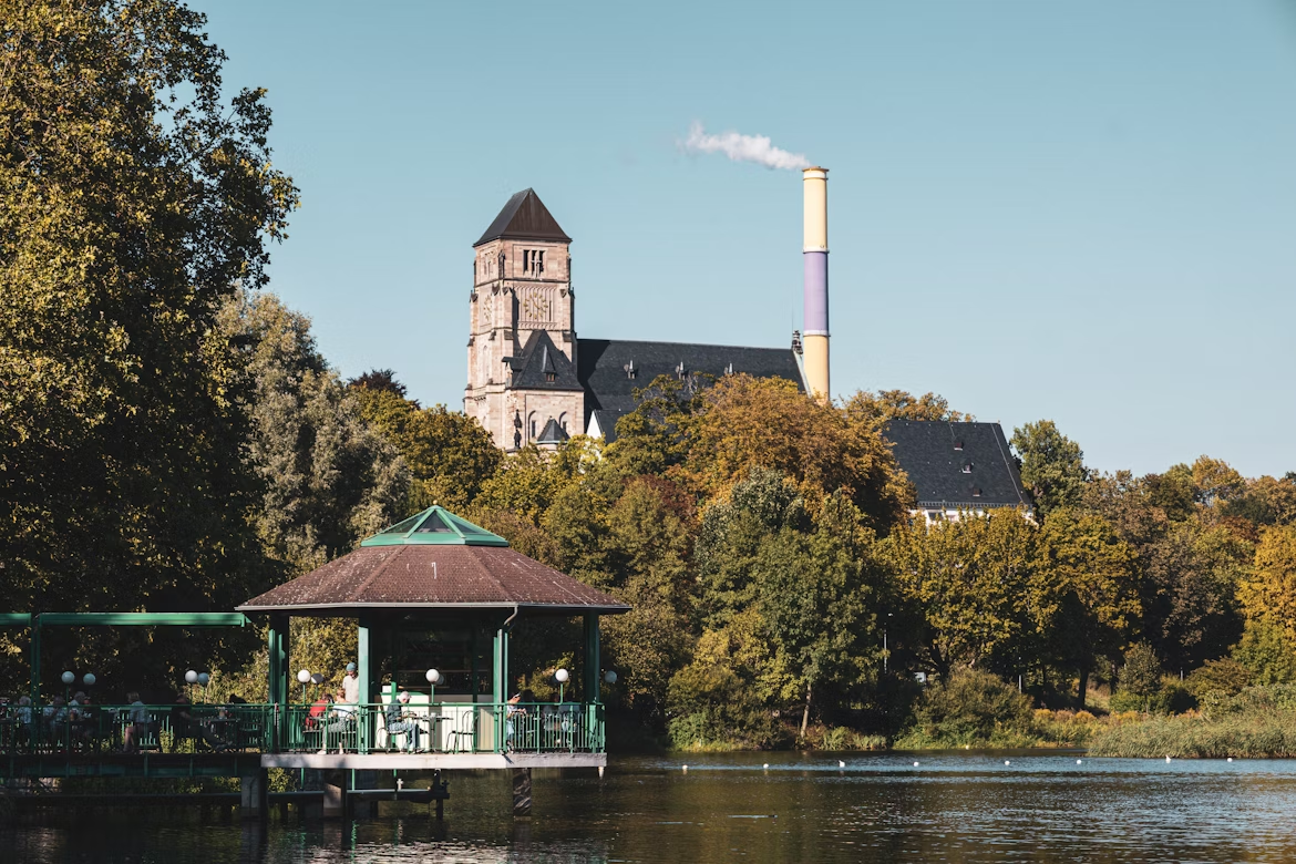 Lakeside view in Chemnitz with a church tower and industrial chimney in the background