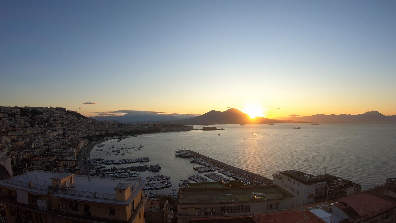 Sunset over the Gulf of Naples with boats and city coastline