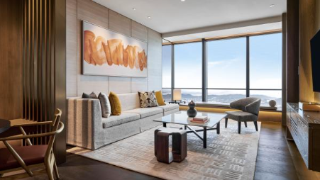 Modern hotel suite interior with panoramic city views through floor-to-ceiling windows
