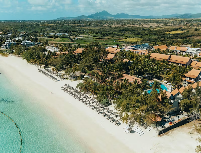 Aerial view of beachfront resort with pool and tropical surroundings