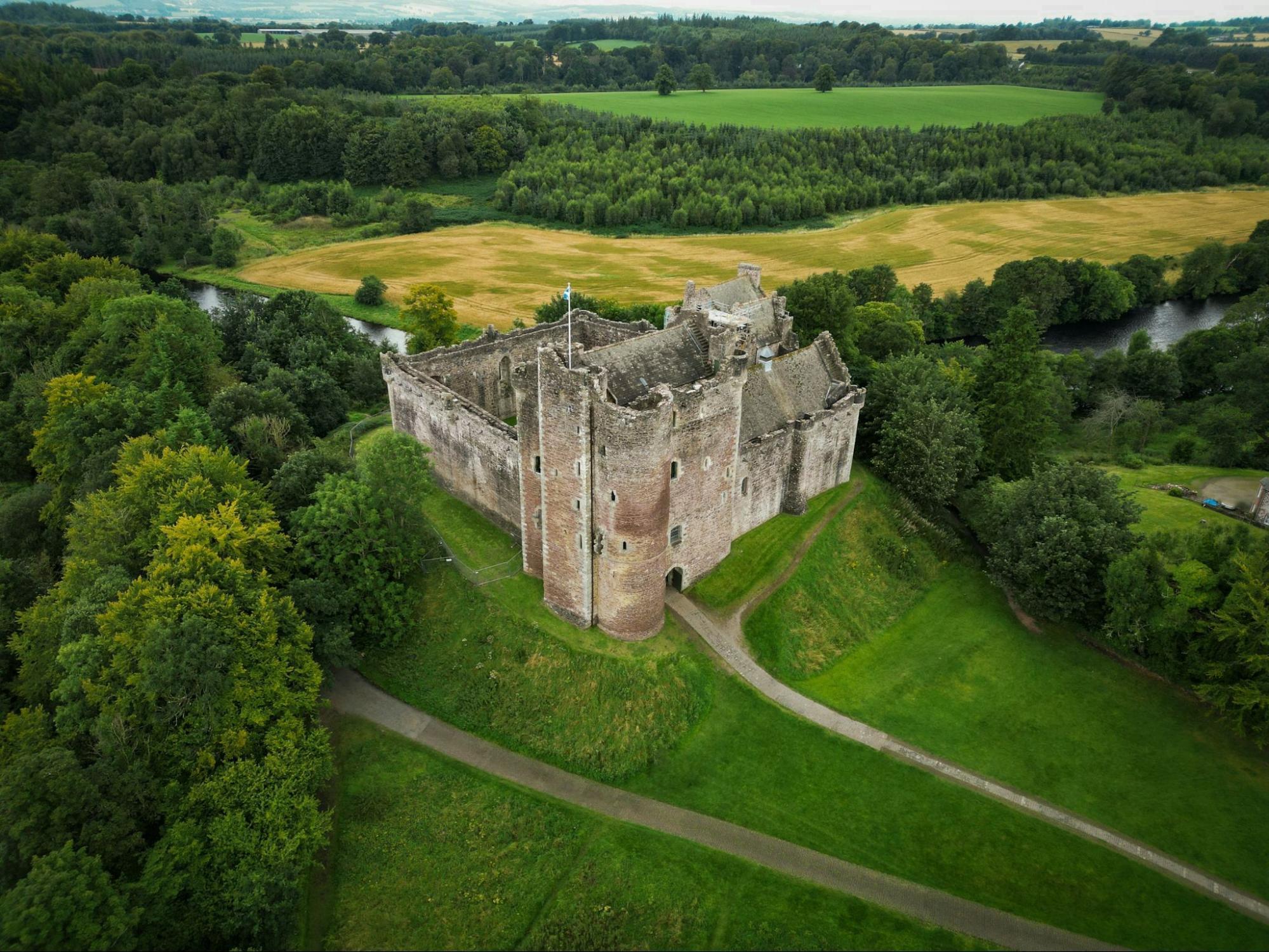 Medieval Scottish castle surrounded by green fields and forest