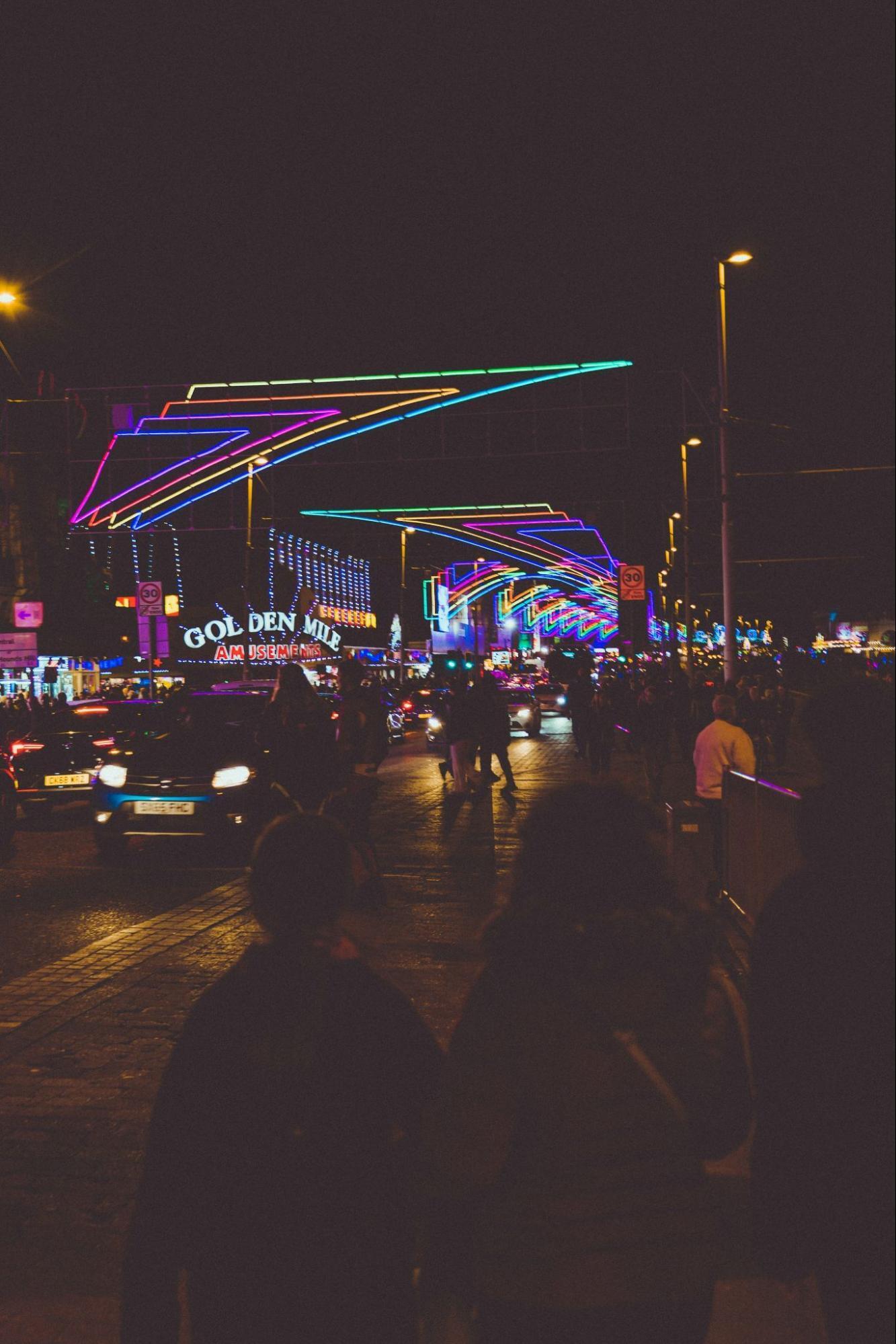 Illuminated street with colorful light arches and evening crowds