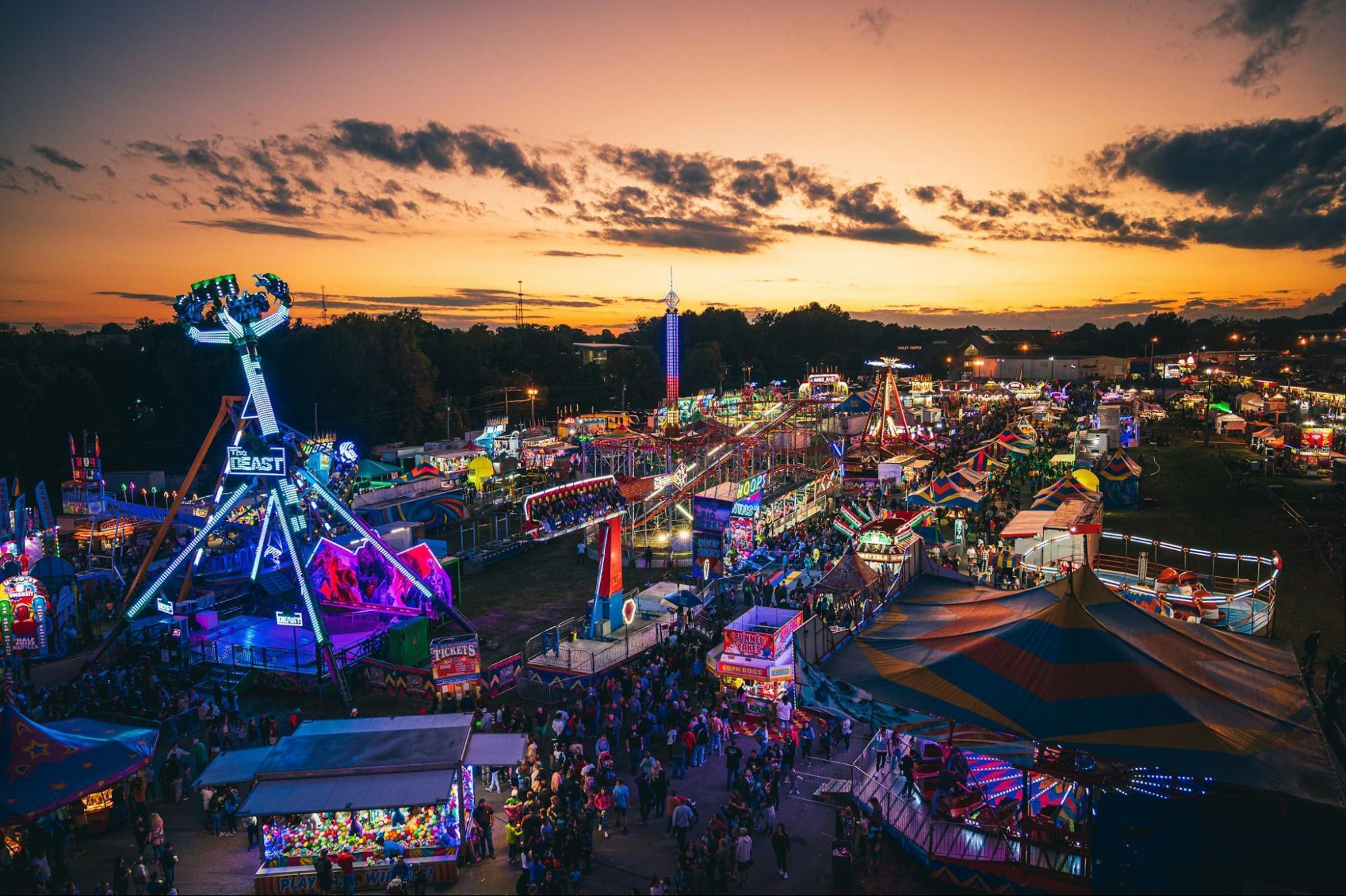 Vibrant evening fairground with rides and colorful lights at sunset