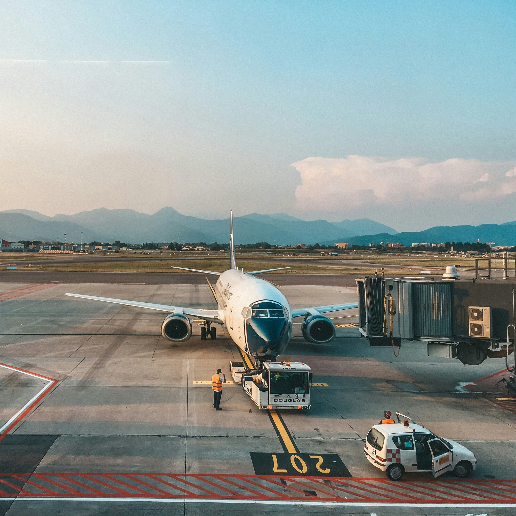A commercial aircraft parked at an Italian airport with ground staff preparing for departure.