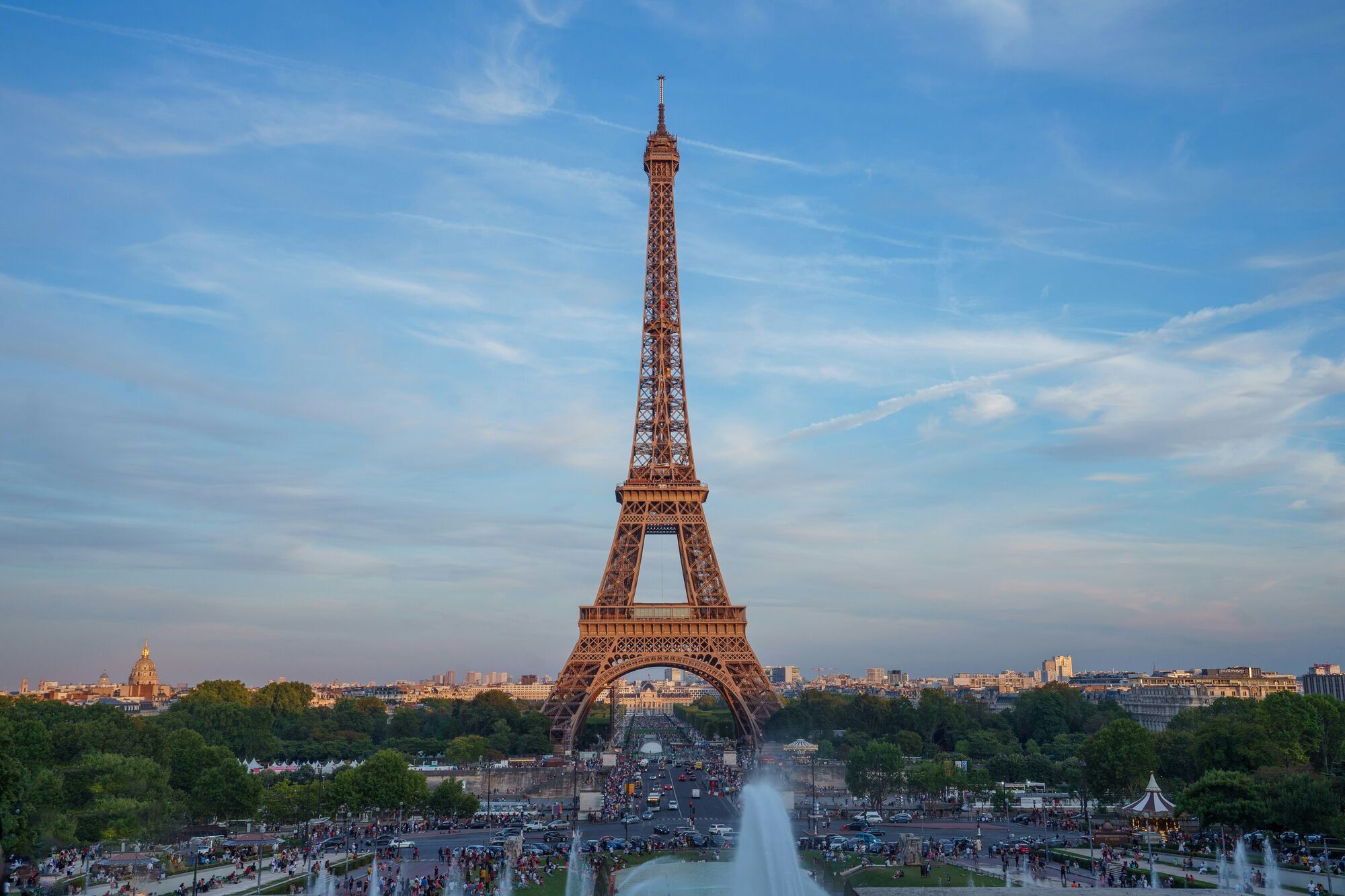 Eiffel Tower in Paris with evening crowds and city traffic