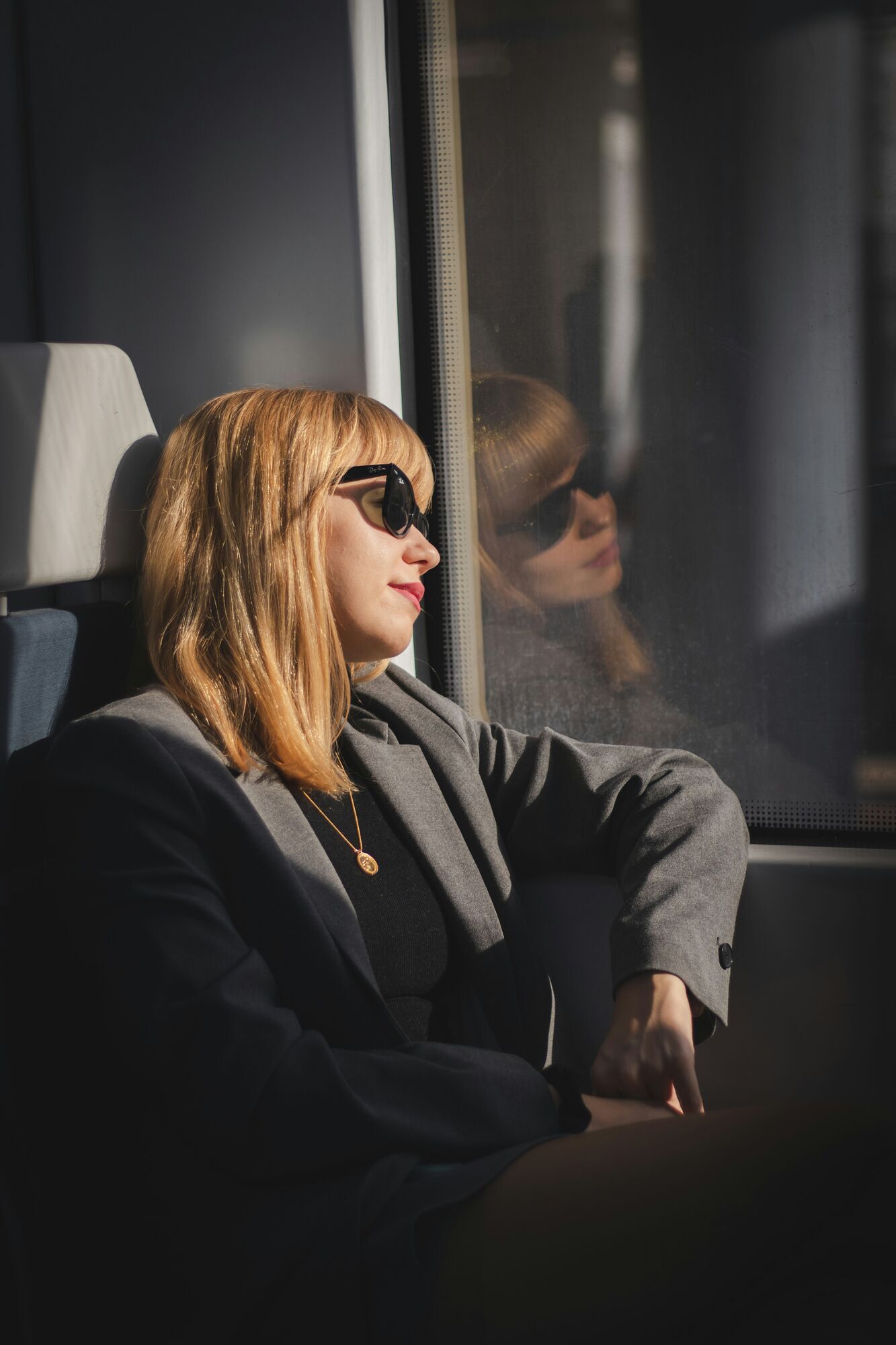 Woman sitting by a train window in daylight