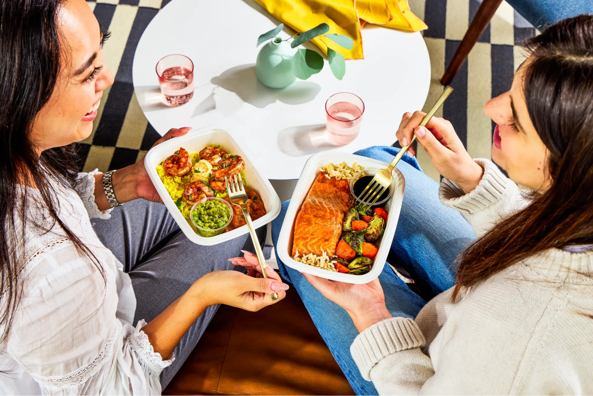 Two women enjoying ready-to-heat chef-prepared meals while sitting indoors