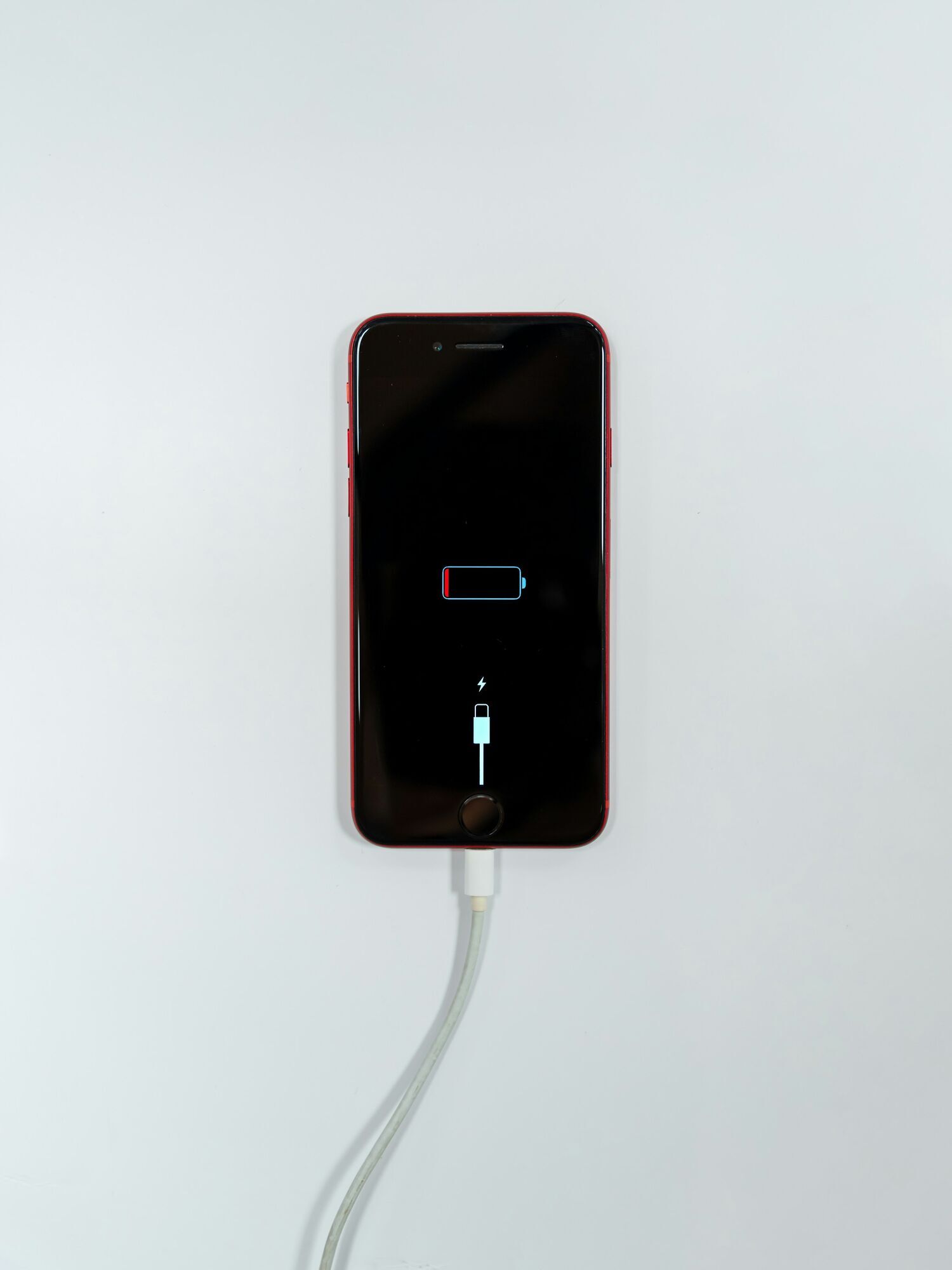 Smartphone displaying a low-battery icon while connected to a charging cable