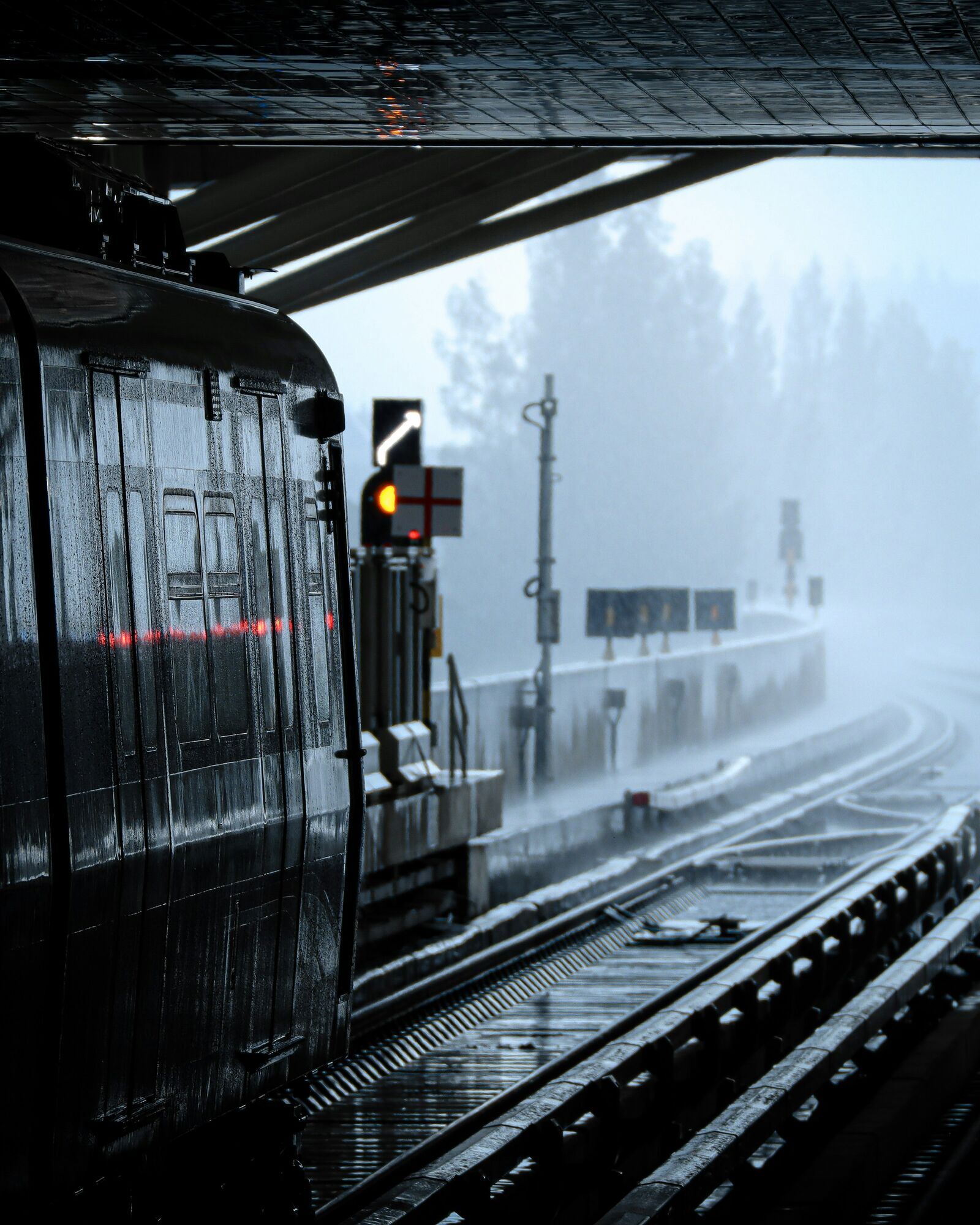 Train waiting at platform during heavy rain and poor visibility