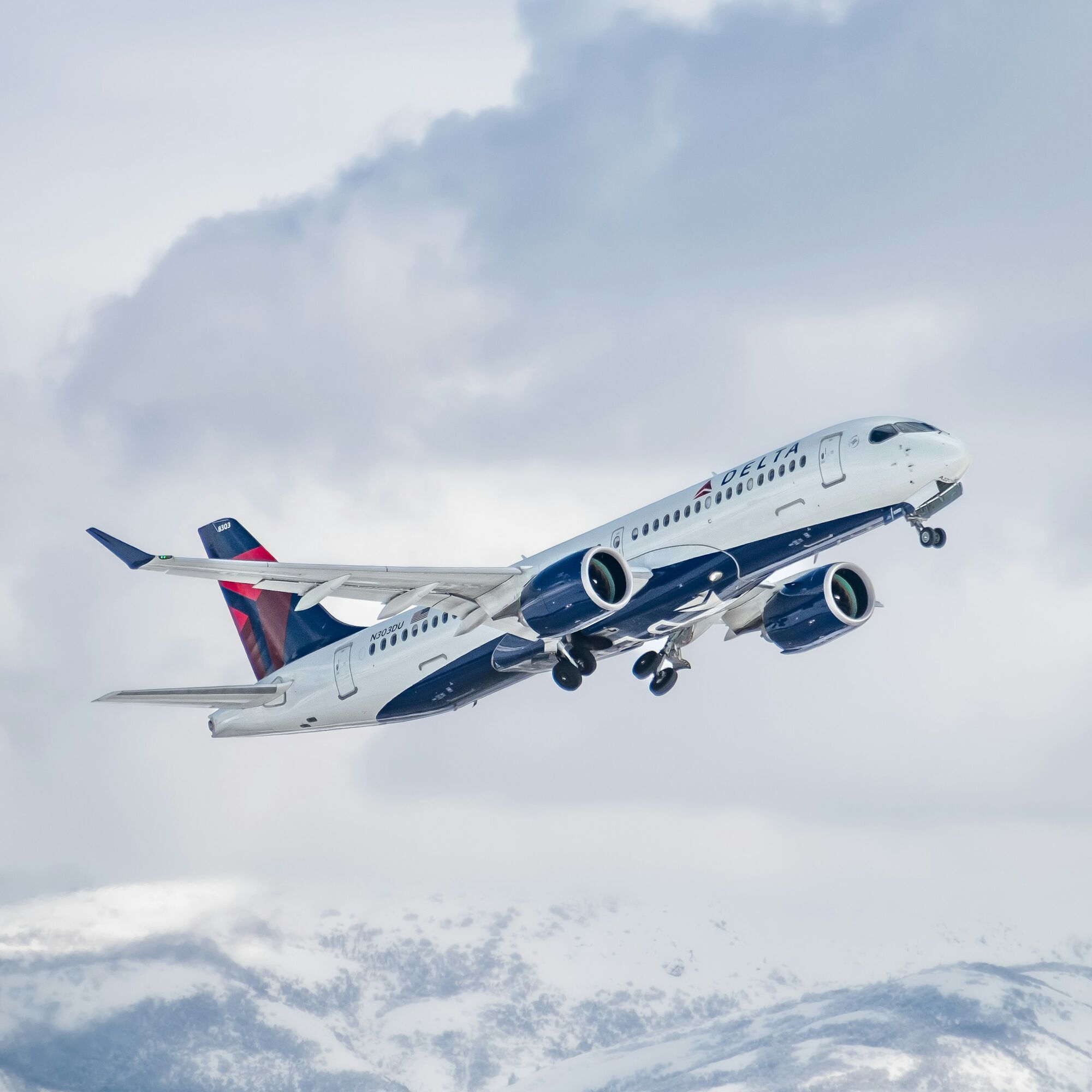 Delta aircraft taking off above snowy mountains
