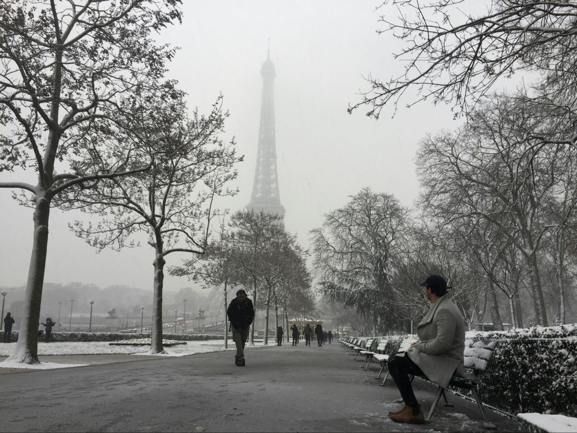 Snow-covered Paris city park with Eiffel Tower during winter weather