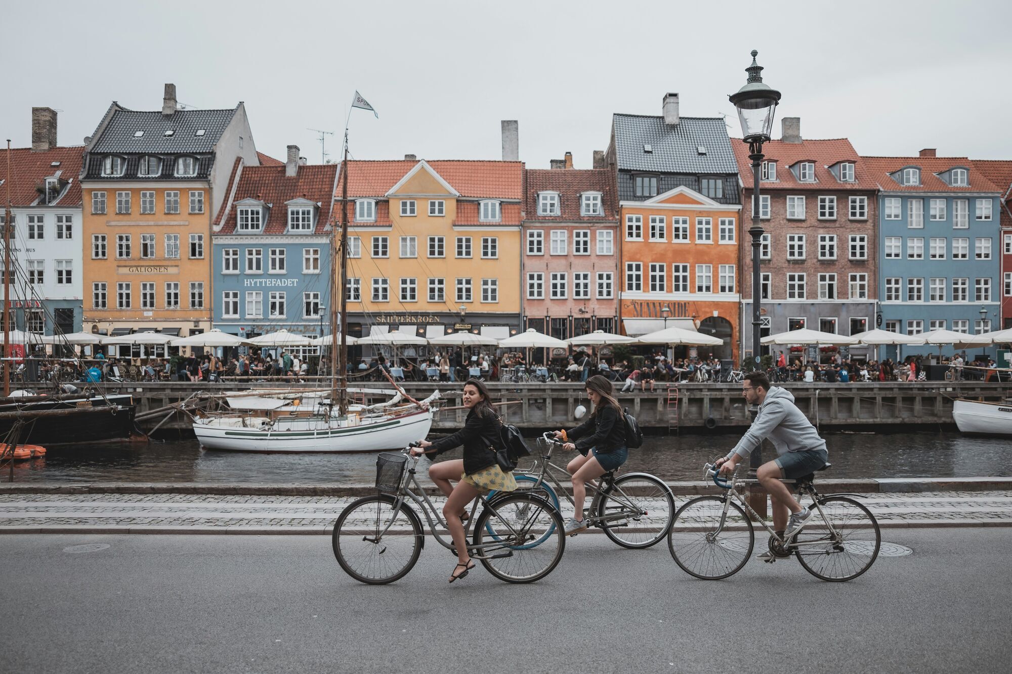 Cyclists passing colourful buildings along Nyhavn canal in Copenhagen