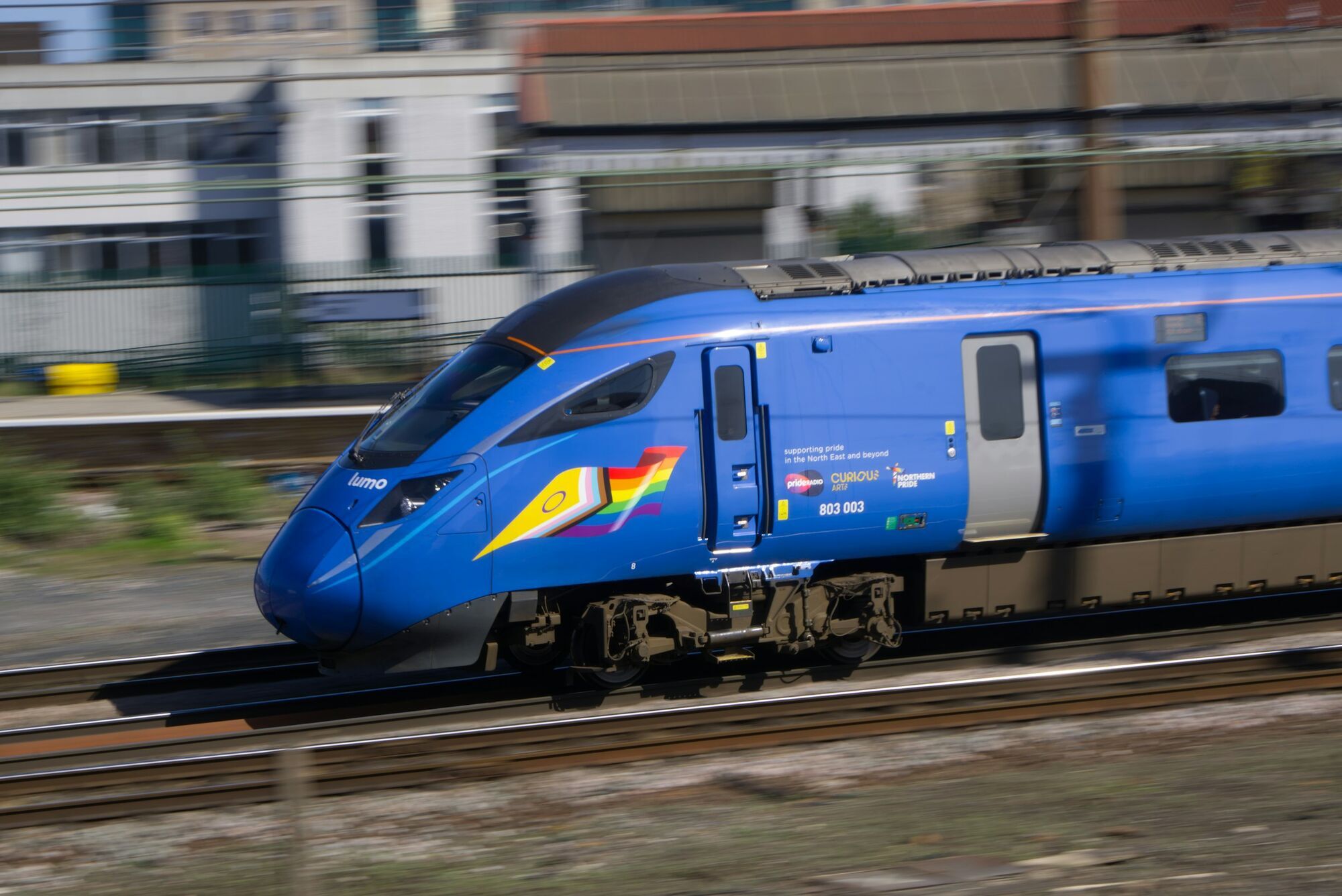 Blue Lumo train travelling along railway tracks